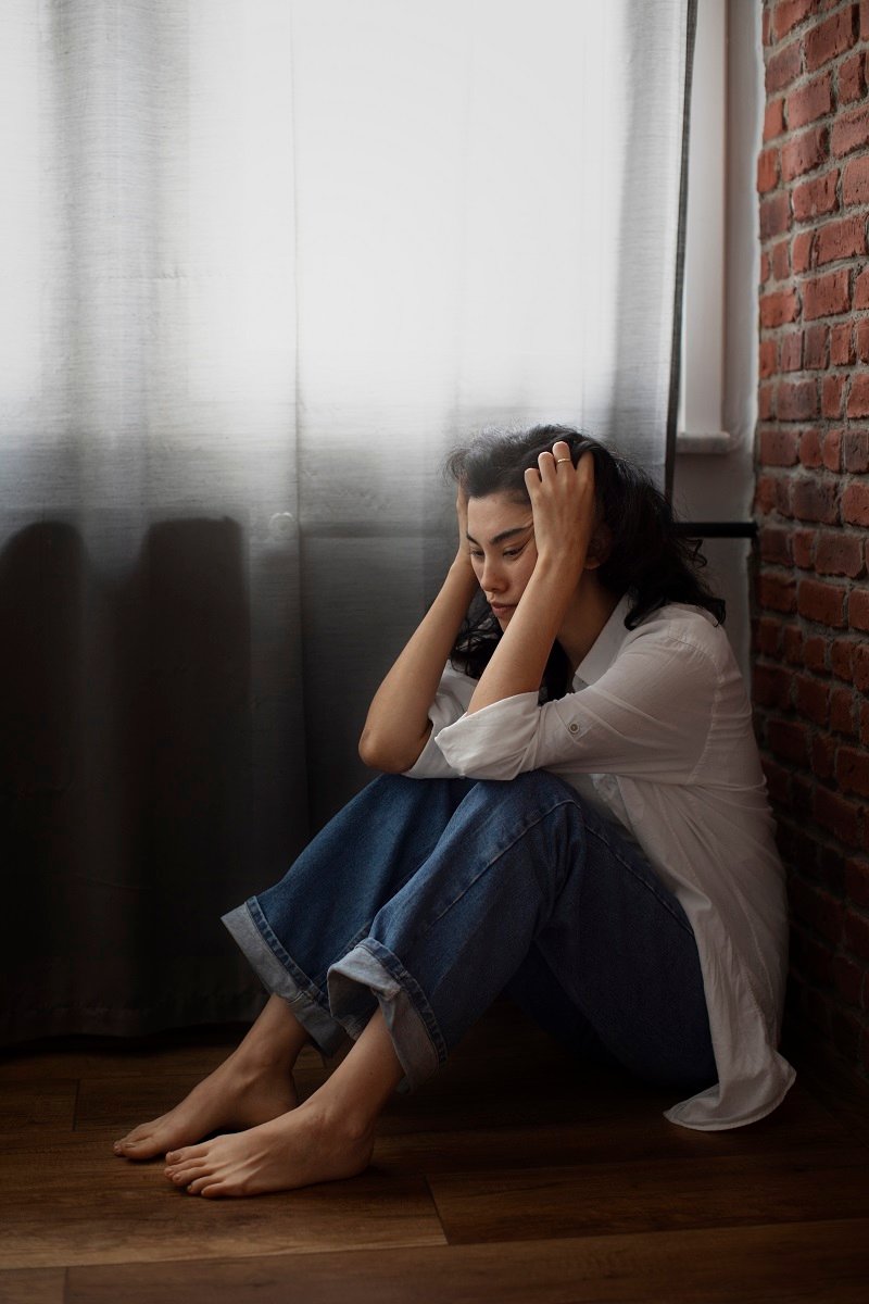 Depressed woman sitting alone in corner holding her head showing severe anxiety and need for Depression Treatment in Bhopal