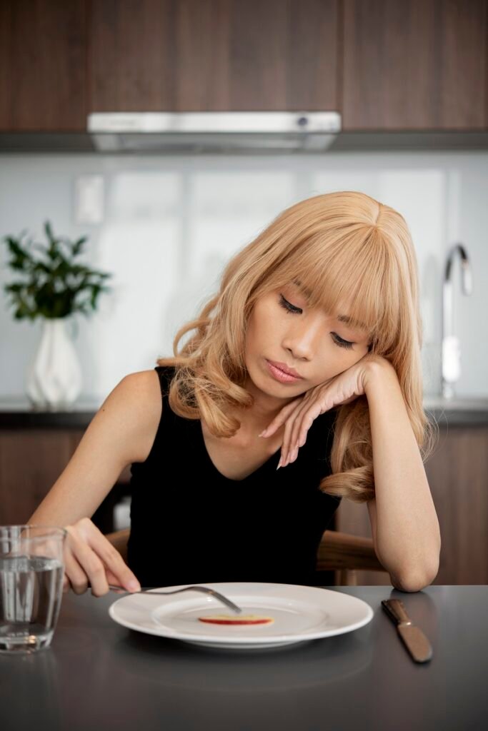 Sad woman sitting at dining table with loss of appetite showing symptoms of depression and need for Depression Treatment in Bhopal