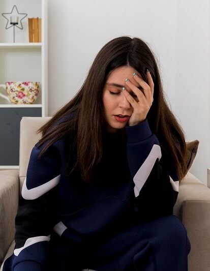 Stressed woman sitting on sofa holding her head showing anxiety and emotional distress requiring Anxiety Treatment in Bhopal
